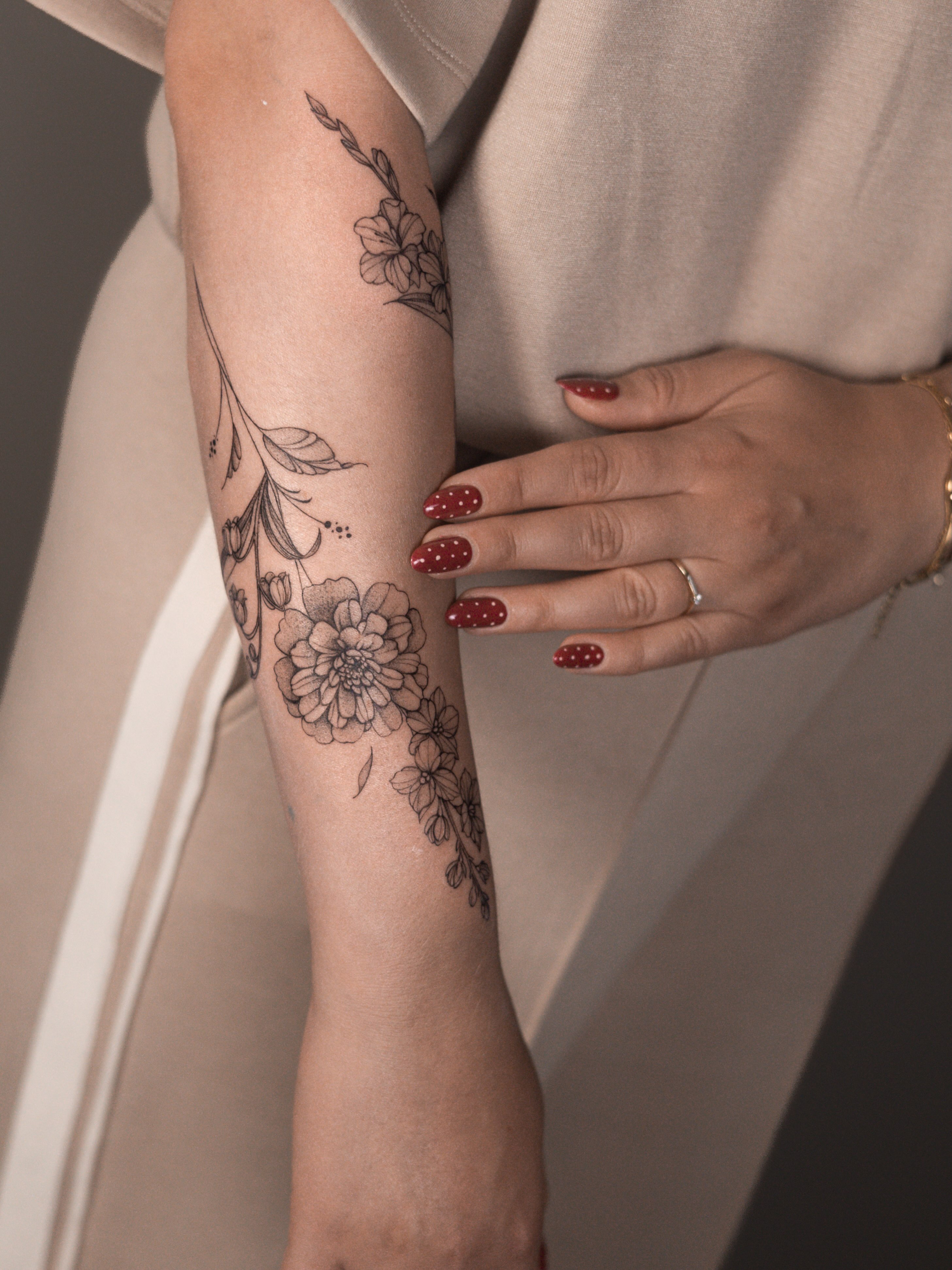 Geboortebloemen van een gezin als botanische tattoo rondom de arm